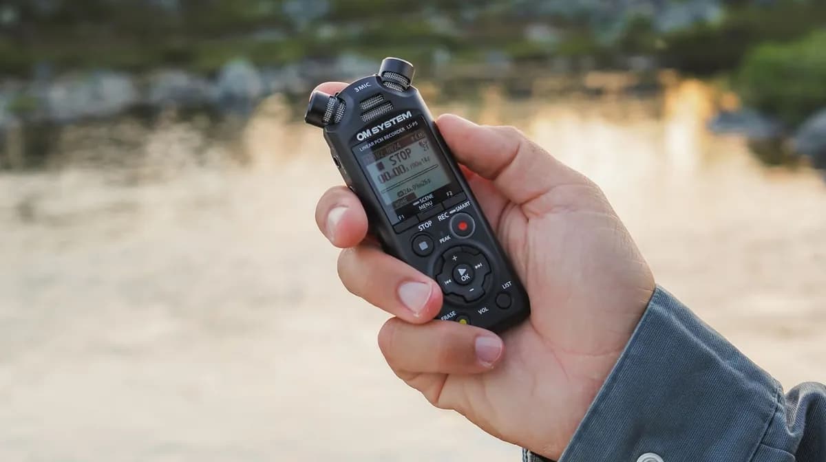 OM System LS-P5 recorder held outdoors by a lake