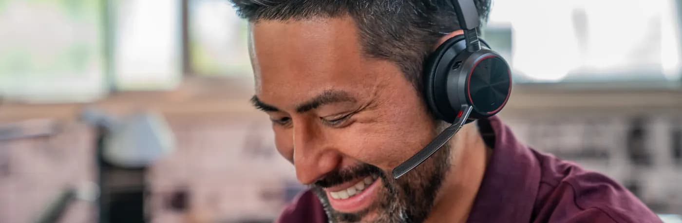 Man in an open-plan office on a call wearing a Poly Voyager Focus 2 headset