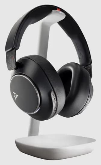 Angled view of Poly Voyager Surround 85 UC stereo headset on wireless charge stand
